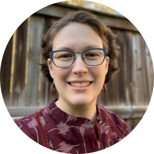 smiling woman with short brown hair and blue glasses